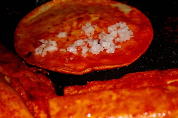 The process of cooking Mexican traditional dish enchiladas with cheese and potatoes