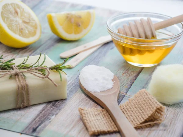 A closeup shot of natural skincare product ingredients: lemon, baking soda, honey, and natural soap