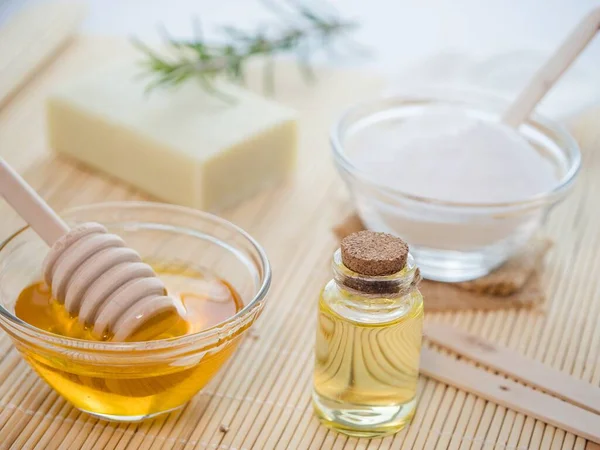 A closeup shot of natural skincare product ingredients: natural soap, baking soda, honey, and essential oil