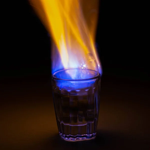 在黑暗的背景下 在玻璃杯中 特写了一杯燃烧的伏特加 — 图库照片