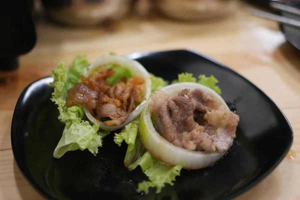 Ein Fleischgericht Mit Zwiebelringen Und Salatblättern Einem Schwarzen Teller Serviert — Stockfoto