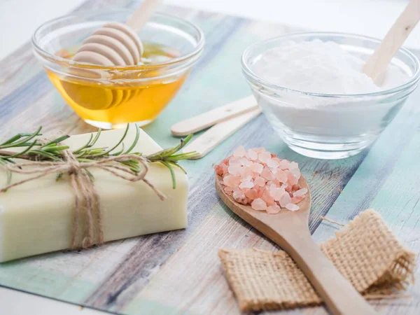 A closeup shot of natural skincare product ingredients: baking soda, honey, natural soap, and sea salt