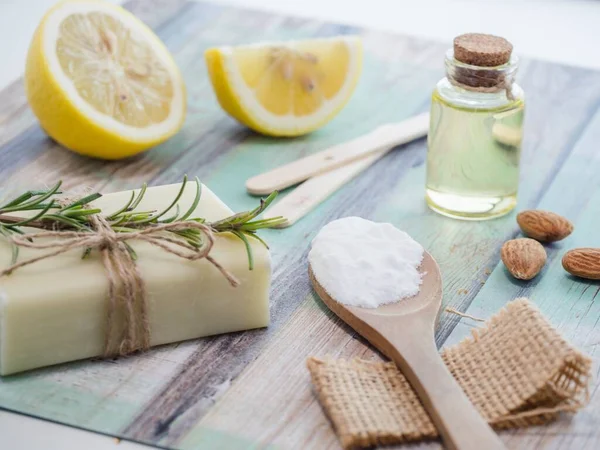 A closeup shot of natural skincare product ingredients: lemon, baking soda, natural soap, and essential oil