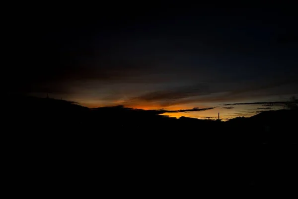 夕暮れ時のオレンジの空の下の丘の風景の息をのむような景色 — ストック写真