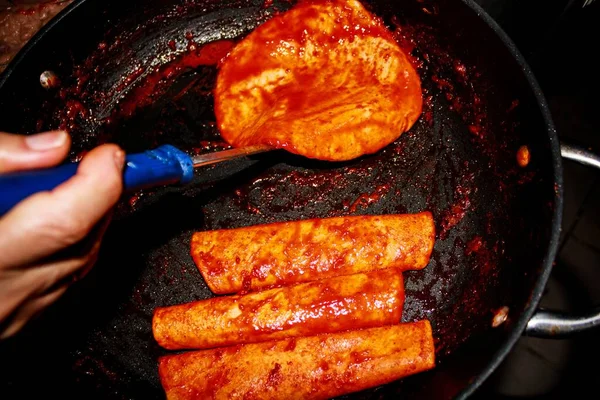 The process of cooking Mexican traditional dish enchiladas with cheese and potatoes