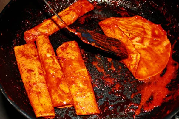 The process of cooking Mexican traditional dish enchiladas with cheese and potatoes