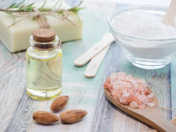 A closeup shot of natural skincare product ingredients: baking soda, sea salt, almonds, essential oil, and natural soap