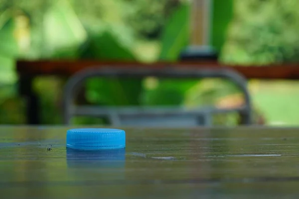 背景がぼやけている木製の表面にプラスチック製の水ボトルキャップの選択的な焦点ショット — ストック写真