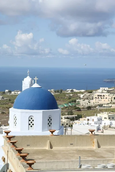 在希腊 圣托里尼一座蓝色圆顶的教堂在白天被建筑物和大海环绕着 这是一张垂直的照片 — 图库照片