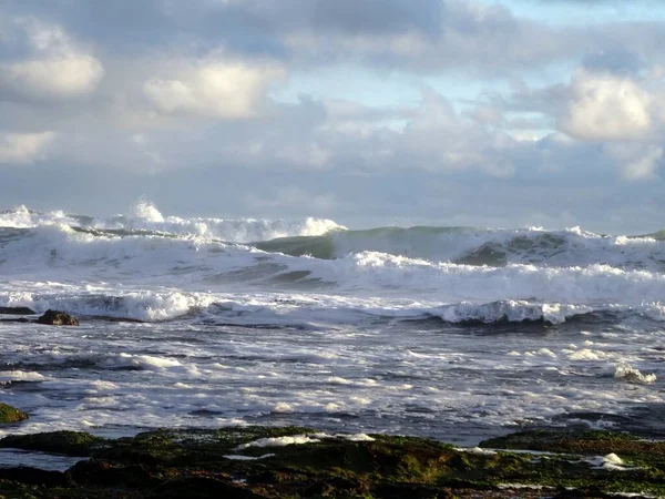 風光明媚な曇りの空の下で海の泡で海岸に打ち寄せる大きな波の美しい景色 — ストック写真