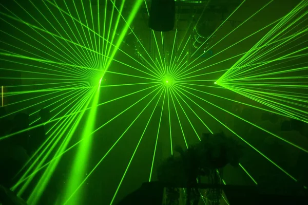 The green laser lights at an outdoor party at night