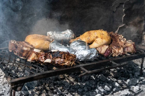 火の上で焼かれる肉とジャガイモのクローズアップ — ストック写真