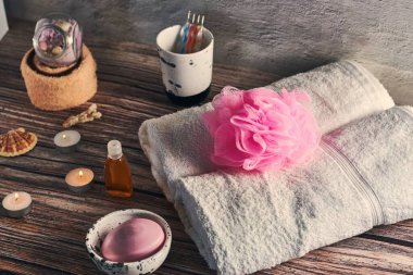 A closeup shot of a set of towels, diffuser, and candles on a wooden surface clipart