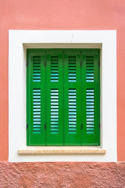 Вертикальный Снимок Зеленых Жалюзи Окна Белой Рамкой Розовой Стене — стоковое фото