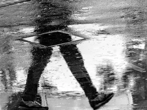 濡れた床に反射した人間のシルエットのクローズアップ灰色のスケールショット — ストック写真