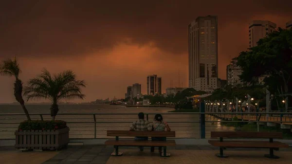 桟橋のベンチに座っているカップルと街の夕日の風景 — ストック写真