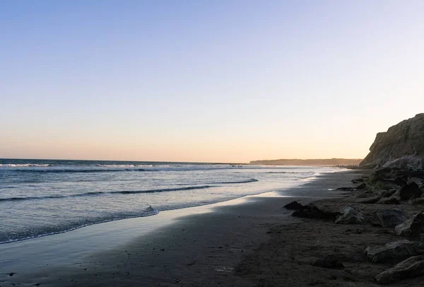 Sziklás Strand Hullámos Tenger Naplementekor — Stock Fotó