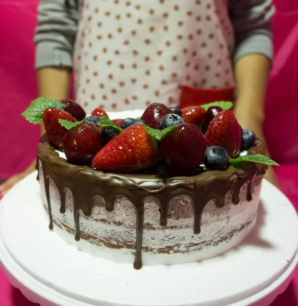 いくつかの新鮮なベリーで飾られ 女の子が提供するチョコレートケーキ — ストック写真