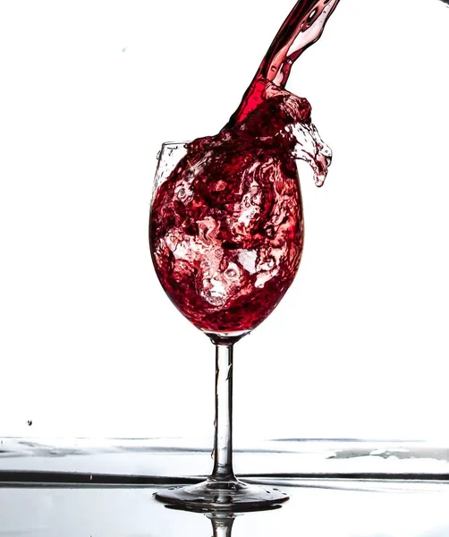 白い背景にガラスに注ぐ赤いジュース — ストック写真
