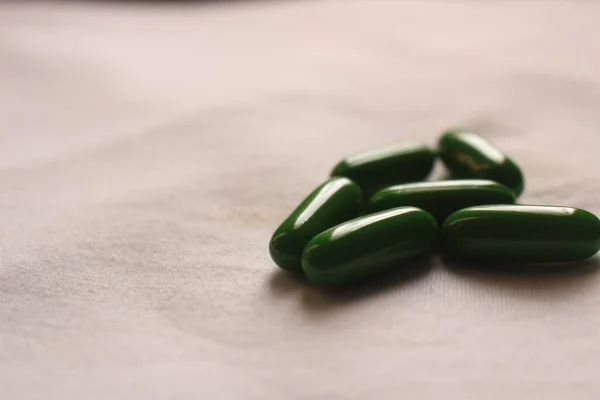 白い布の上に緑の医療用丸薬の浅いフォーカスクローズアップショット — ストック写真