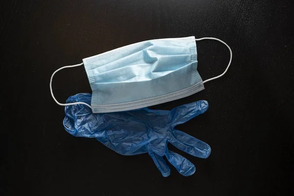 Eine Schützende Gesichtsmaske Und Ein Blauer Plastikhandschuh Auf Schwarzem Hintergrund — Stockfoto