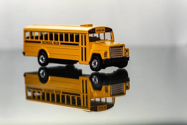 Yansıyan Bir Yüzey Üzerinde Sarı Oyuncak Okul Otobüsünün Yakın Çekimi — Stok fotoğraf