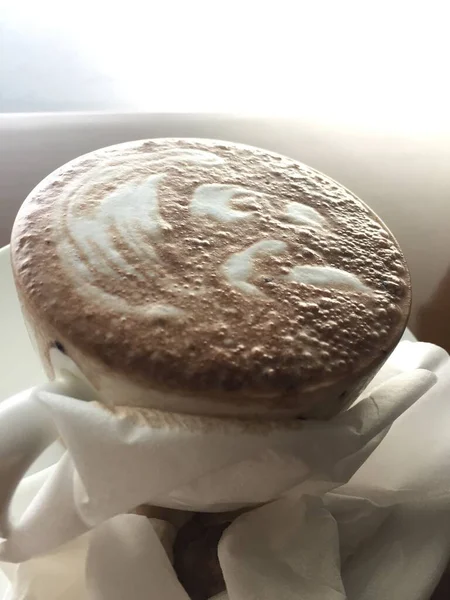 白い背景の上に泡のあるコーヒーカップの垂直ショット — ストック写真