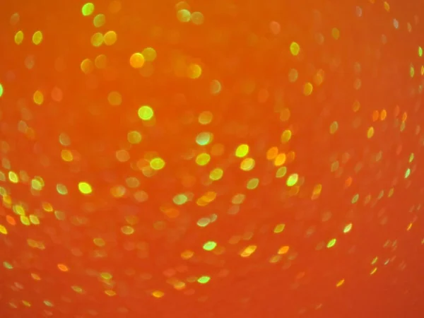 壁紙のためのオレンジ色の背景に小さな多色のボケの光の抽象的なショット — ストック写真