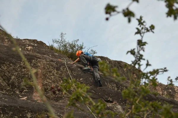 白い空を背景に昼間の山に登る男 — ストック写真