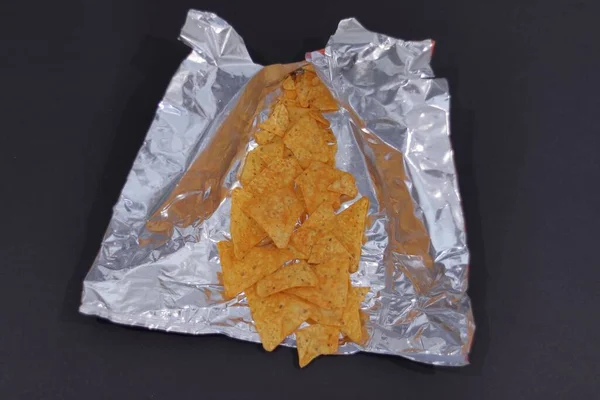 A closeup shot of tortilla chip in an opened package isolated on a black background