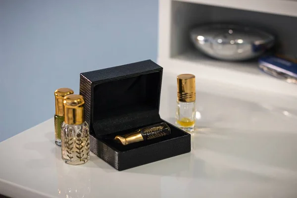 A soft focus of small perfume bottles with golden caps and a black box