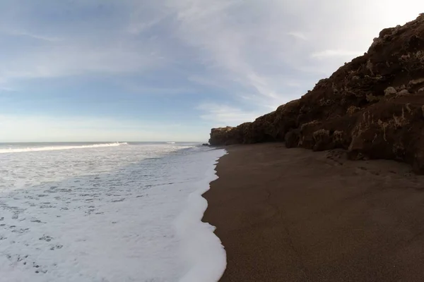 Nahaufnahme Eines Welligen Ozeans Mit Sandstrand Und Einem Felsigen Berg — Stockfoto