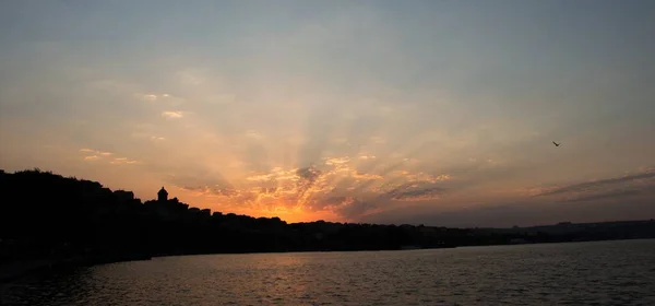 Eine Faszinierende Aufnahme Eines Orangefarbenen Sonnenuntergangs Vor Laubbergen Und Wasser — Stockfoto