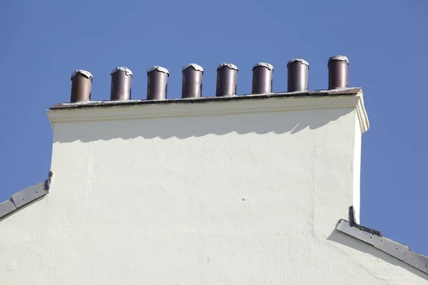 青い空の下に円形のパイプを持つ建物の屋根 — ストック写真