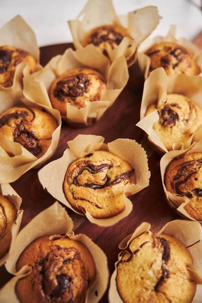 stock image A vertical high angle shot of delicious chocolate muffins on a wooden plate on a white table