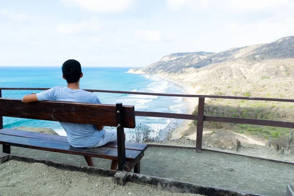 Młody Człowiek Siedzący Ławce Patrzący Morze Otoczony Wzgórzami Dzień — Zdjęcie stockowe