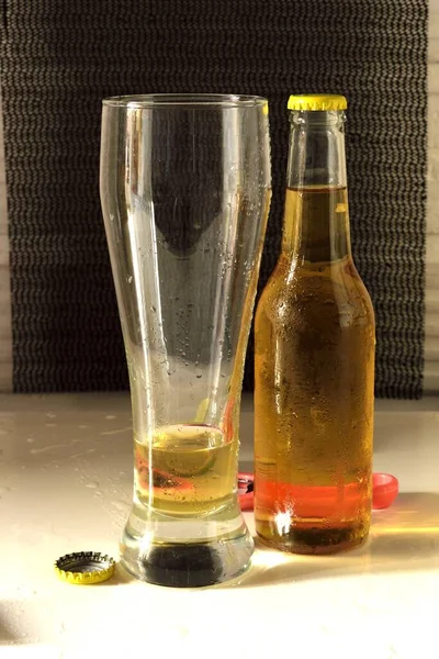 白いテーブルの上にガラスと冷たいビールのボトルの垂直ショット — ストック写真