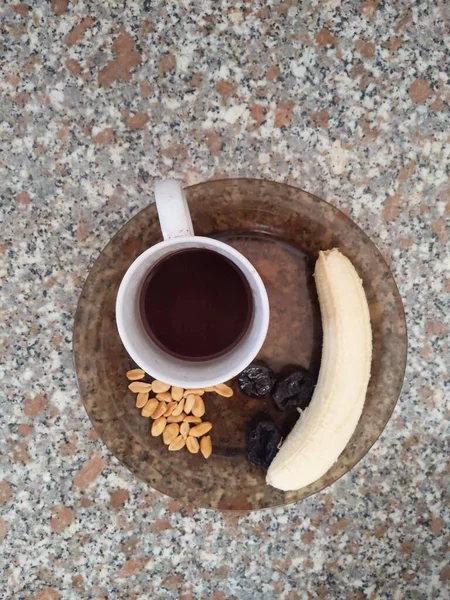 板の上にバナナとピスタチオの皮をむいたコーヒーカップを角度の高いショット — ストック写真