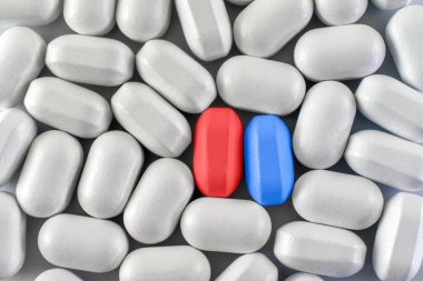 A closeup shot of red and blue pills between similar shaped white pills - choice concept clipart