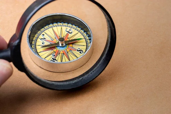 Closeup Shot Male Holding Magnifying Glass Compass Brown Surface — Stock Photo, Image