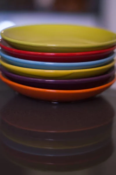 Ein Satz Mehrfarbiger Teller Der Sich Auf Einem Küchentisch Spiegelt — Stockfoto
