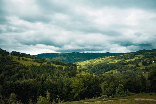 Een Landschap Van Heuvels Bedekt Met Groen Onder Een Bewolkte — Stockfoto