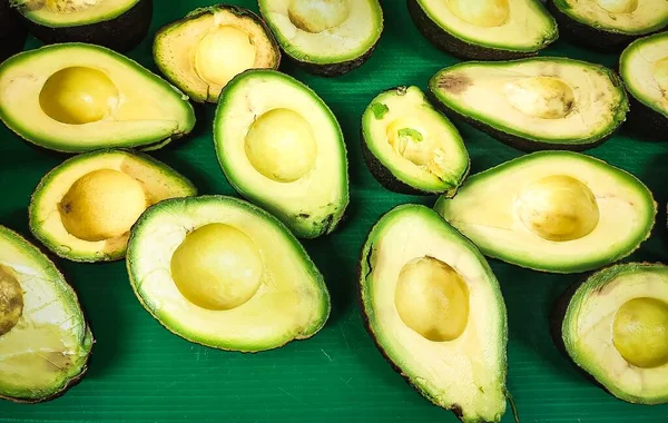 Veel Avocado Doormidden Gesneden Stenen Het Groene Oppervlak Verwijderd — Stockfoto