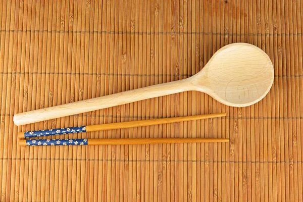 用木勺和筷子在竹子桌布上拍摄的高角镜头 — 图库照片