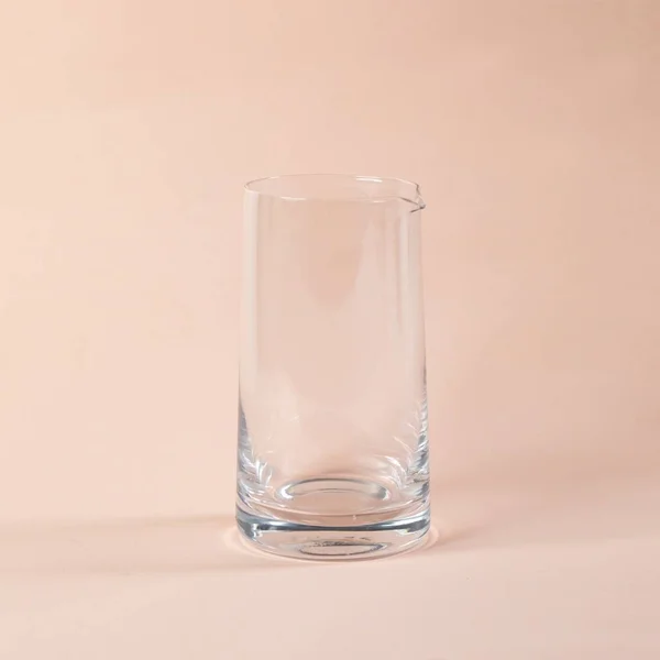 Een Doorzichtige Glazen Kan Een Beige Ondergrond — Stockfoto