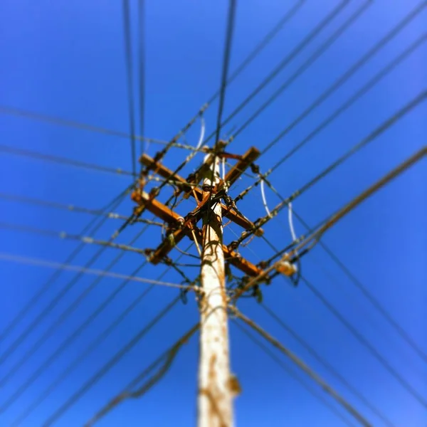 Açık Mavi Gökyüzünün Altında Elektrik Kabloları Olan Bir Direğin Alçak — Stok fotoğraf