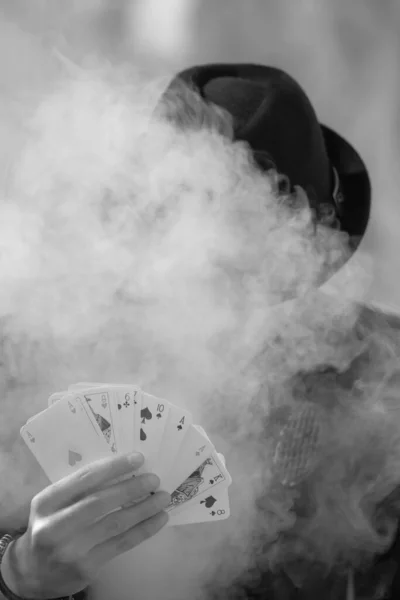 一个神秘的男性游戏玩家手拿着烟熏扑克牌的灰度画像 — 图库照片