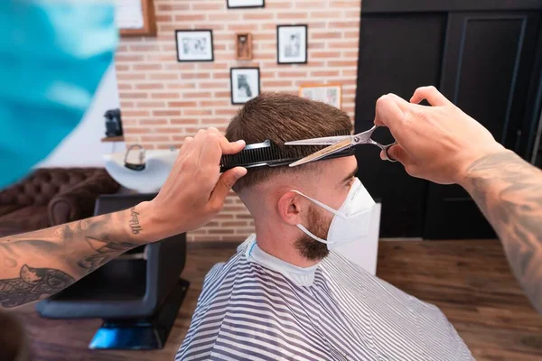 Ein Junger Friseur Schneidet Einem Männlichen Kunden Mit Einer Gesichtsmaske — Stockfoto