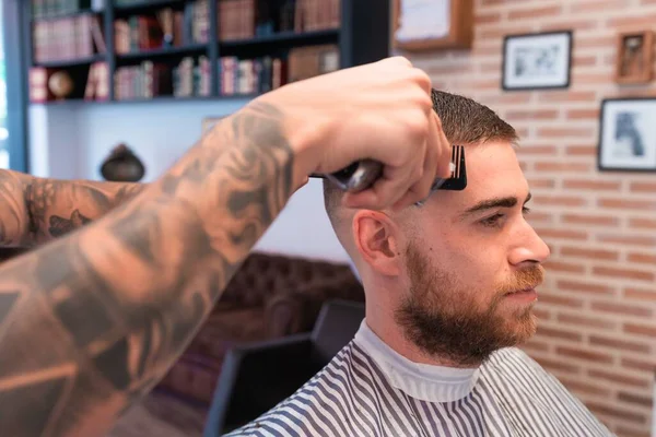 Młody Fryzjer Obcinający Męskie Włosy Obcinaczem Włosów Salonie Fryzjerskim — Zdjęcie stockowe