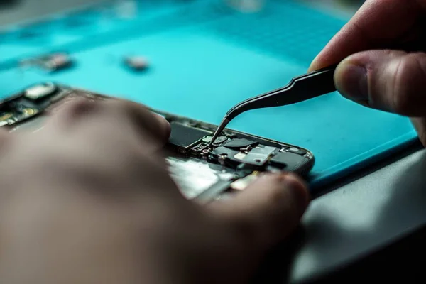 A closeup shot of a person repair a mobile in mobile repair smartphone workshop